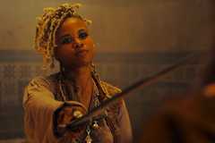 A woman pointing a sword at a man off screen